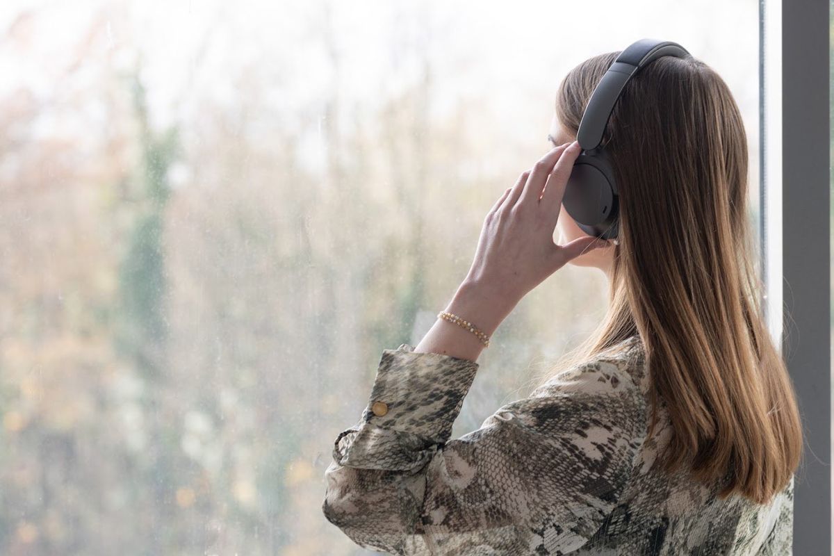 Eine Frau mit Kopfhörern schaut aus einem Fenster.