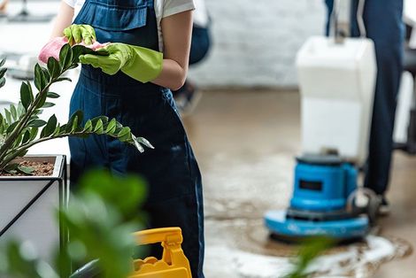 Eine Frau mit grünen Handschuhen reinigt eine Fabrik in einem Büro.