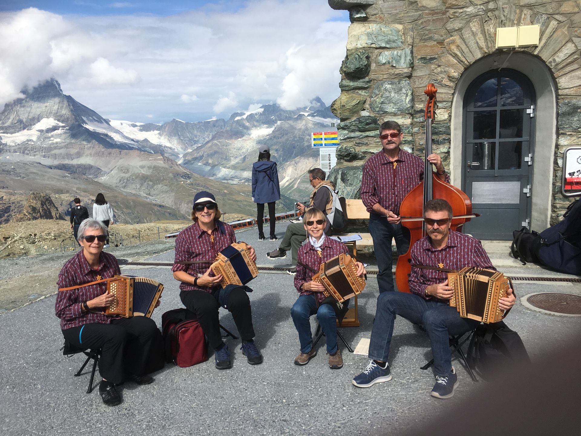 Drei Tassen Cappuccino stehen auf einem Holztisch neben Topfpflanzen.