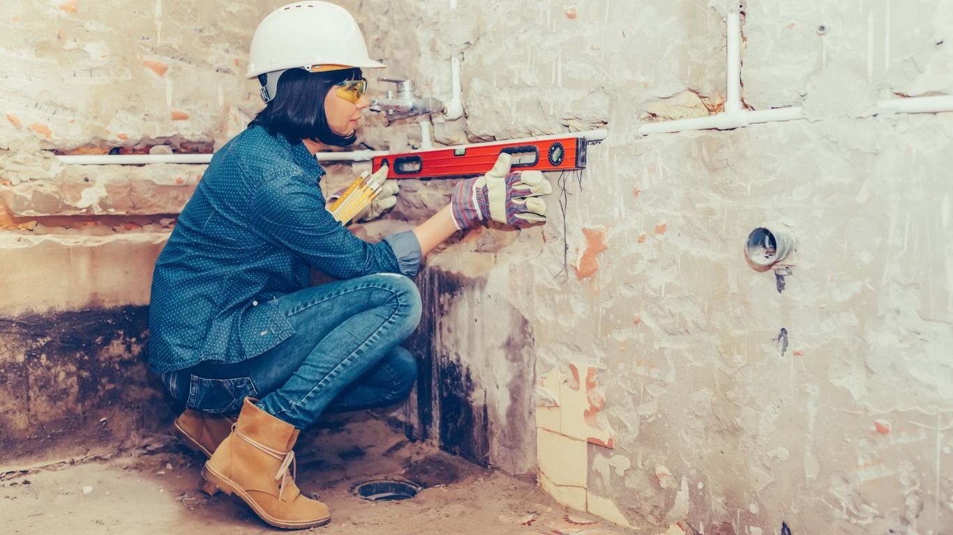 Una mujer está midiendo una pared con un nivel.