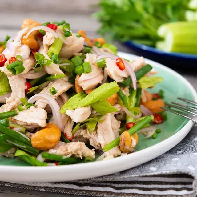 Un plato de comida con pollo y verduras sobre una mesa con un tenedor.