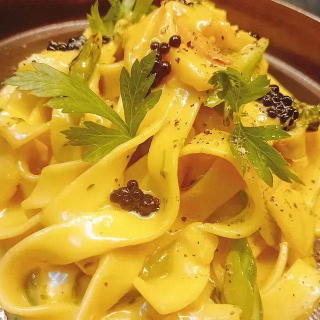 Un primer plano de un plato de pasta con salsa y verduras.