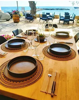 Una mesa de madera con platos, vasos y cubiertos sobre ella.