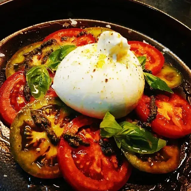 Un plato de comida con tomates y mozzarella encima.
