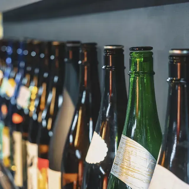 Una fila de botellas de vino están alineadas en un estante