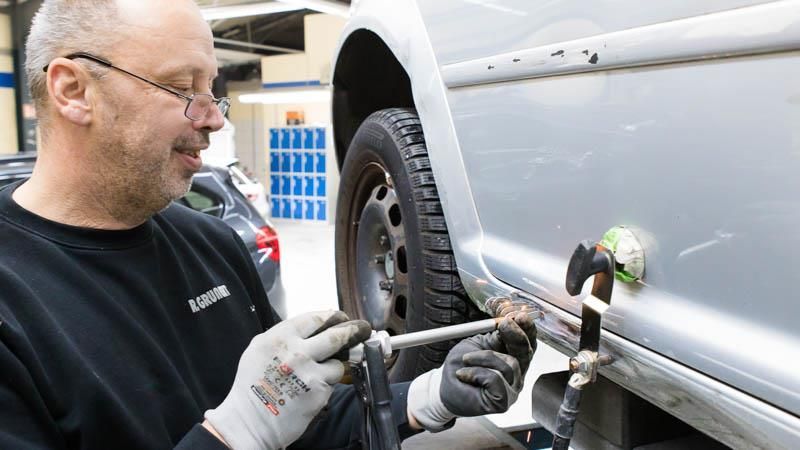 Ein Mann arbeitet in einer Garage an einem Auto.