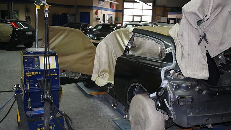 In einer Garage wird an einem schwarzen Auto gearbeitet