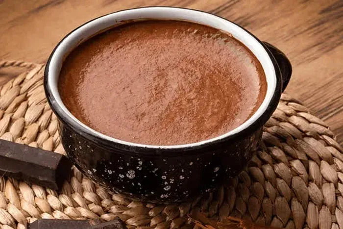 Un tazón de sopa de chocolate está sobre un mantel sobre una mesa de madera.