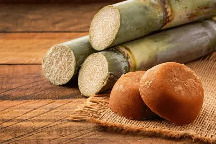 Caña de azúcar y jaggery sobre una mesa de madera.