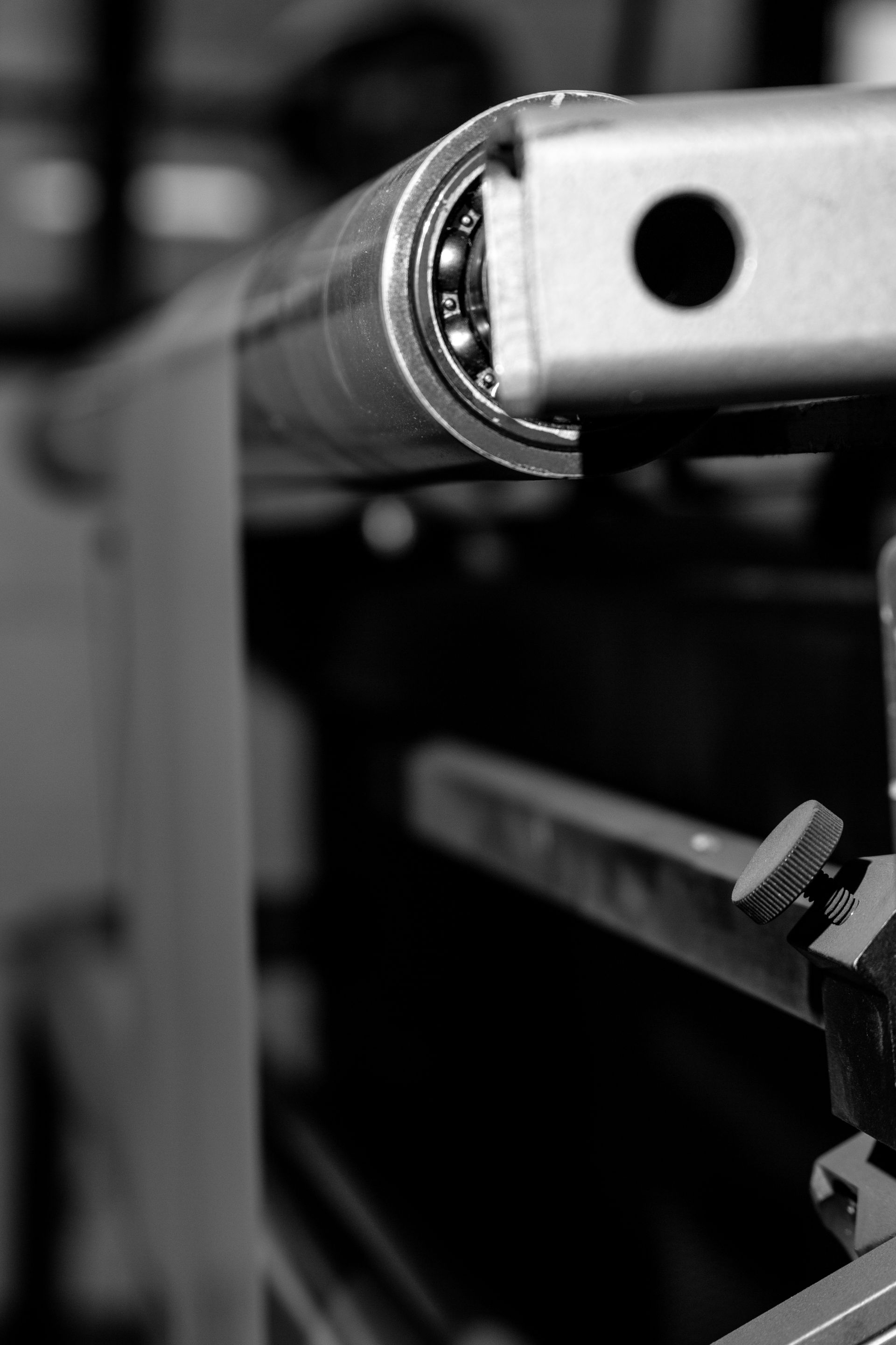 Gros plan en noir et blanc d'un composant de machine comportant un rouleau métallique, des roulements à billes et un bouton de tension.