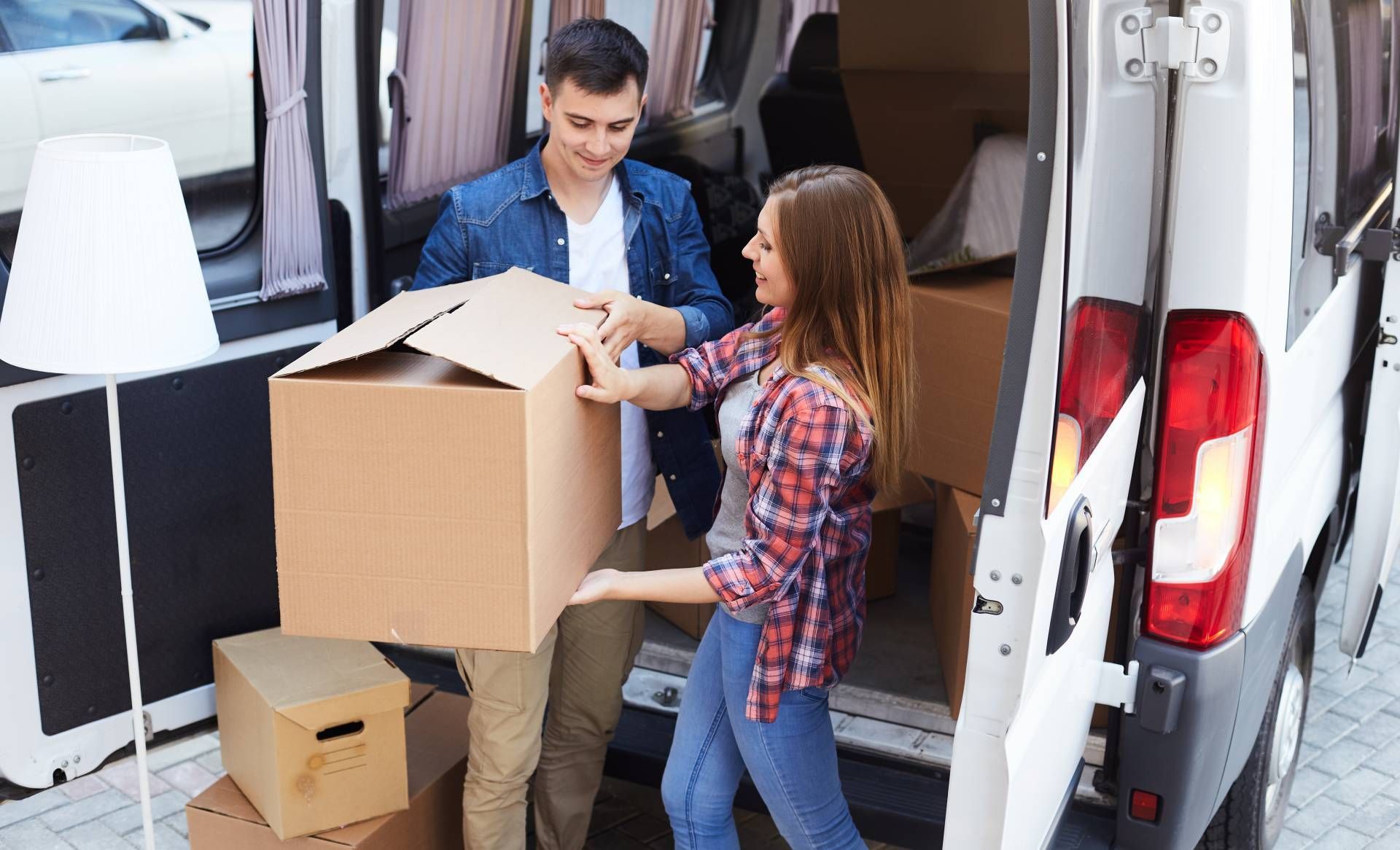 Ein Mann und eine Frau laden Kisten in einen Lieferwagen.