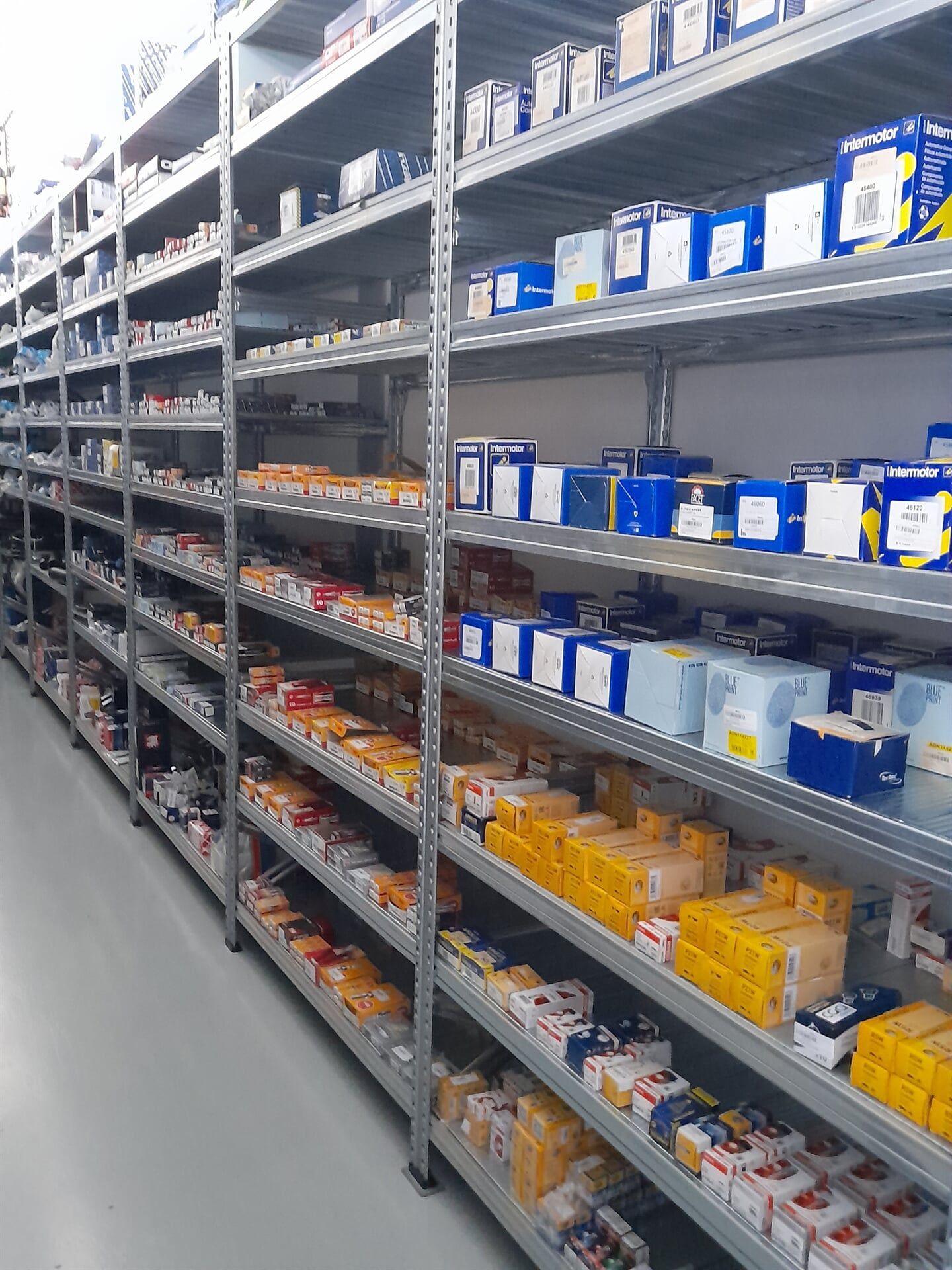 Prateleiras repletas de diversas caixas e embalagens em um armazém ou depósito.