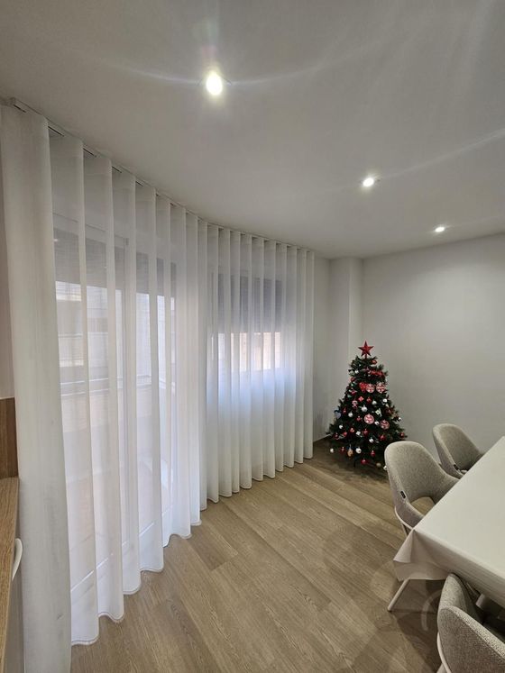 Sala de estar moderna con sofá seccional gris, mesa de centro blanca y televisor sobre un soporte blanco.