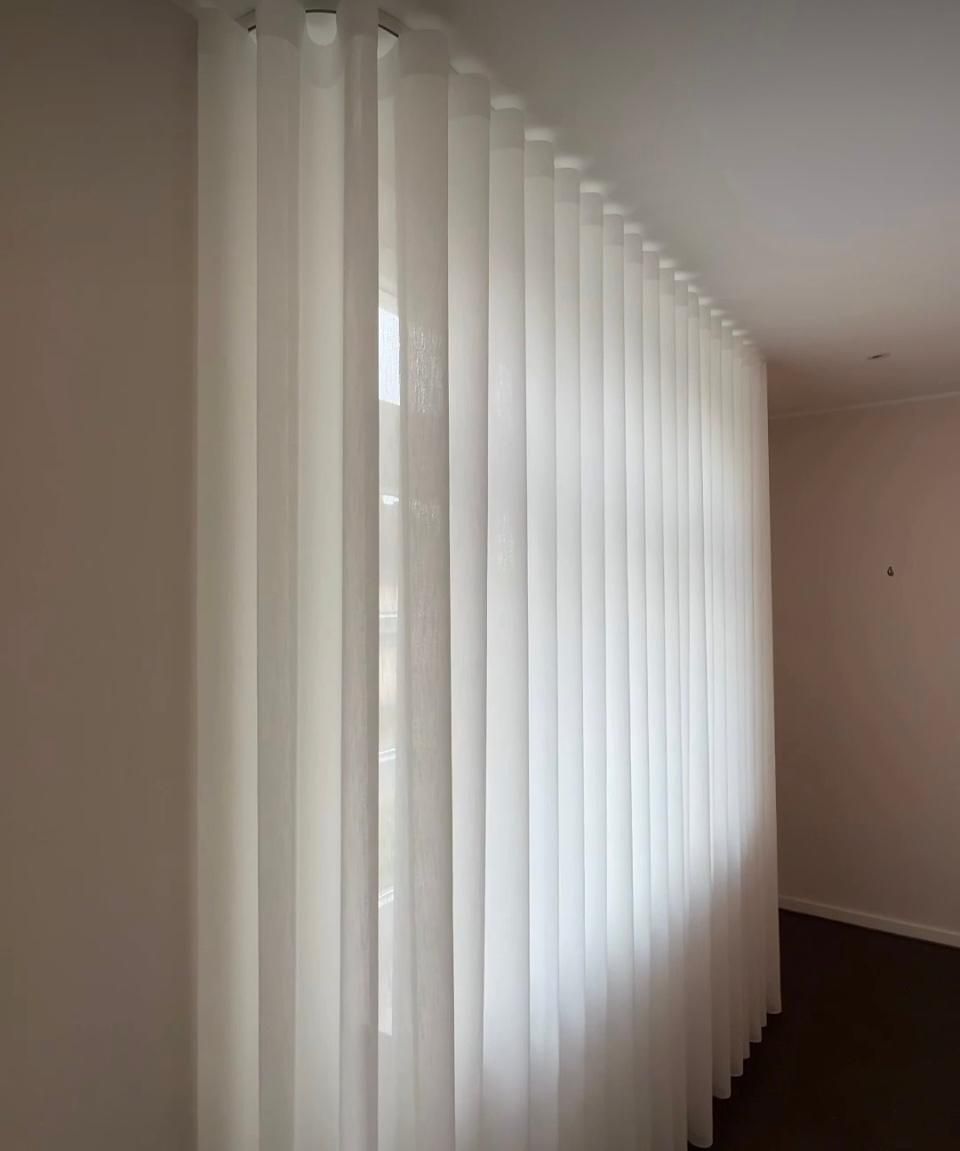 Persiana de ventana a rayas oscuras por donde se filtra la luz del día en una habitación.