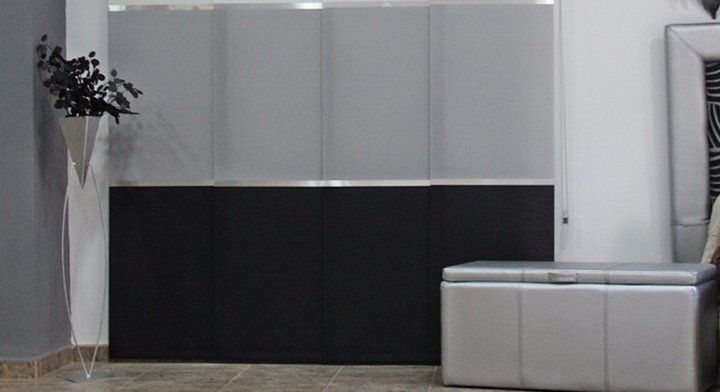 Sala de estar moderna con gabinetes blancos, paneles inferiores negros y un sofá-banco gris claro.