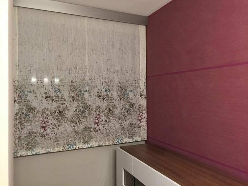 Pared decorativa rosa junto a una cortina transparente estampada sobre una encimera de madera en una habitación moderna.