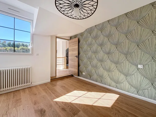 Chambre rénovée avec parquet bois, mur à motifs et lumière naturelle