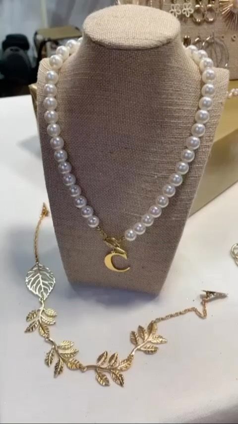 Un collar con perlas y hojas de oro está sobre un maniquí.