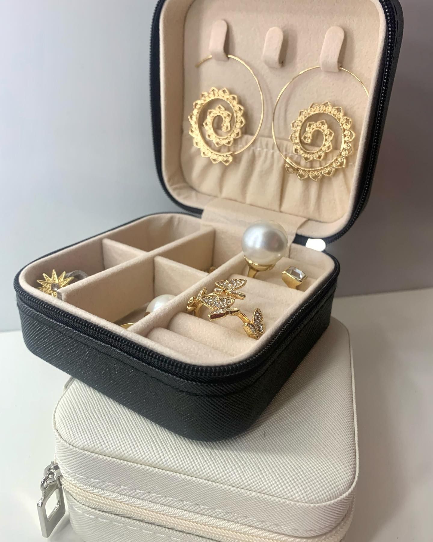 Un joyero en blanco y negro lleno de pendientes y anillos.