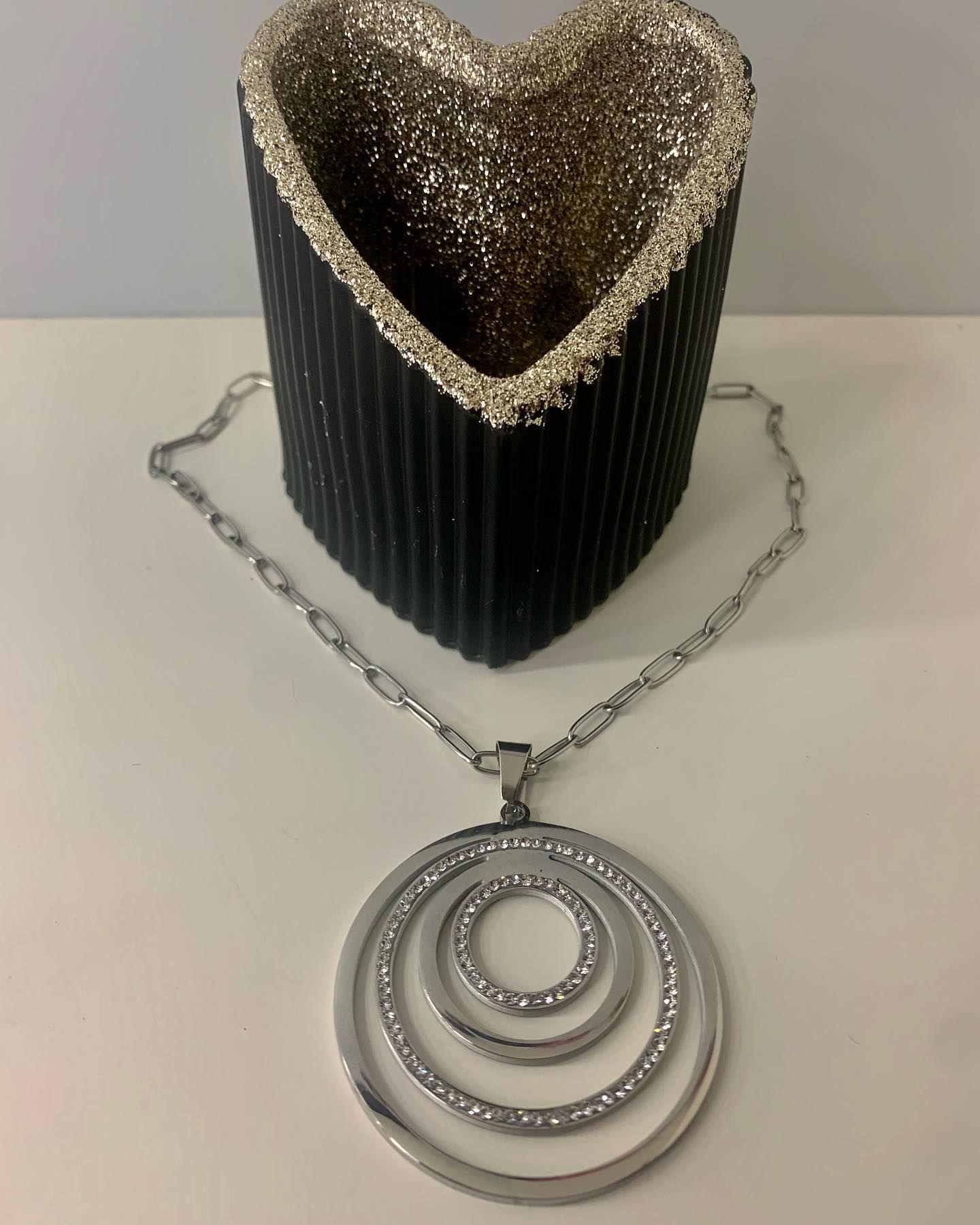 Un collar está sobre una mesa junto a un jarrón con forma de corazón.