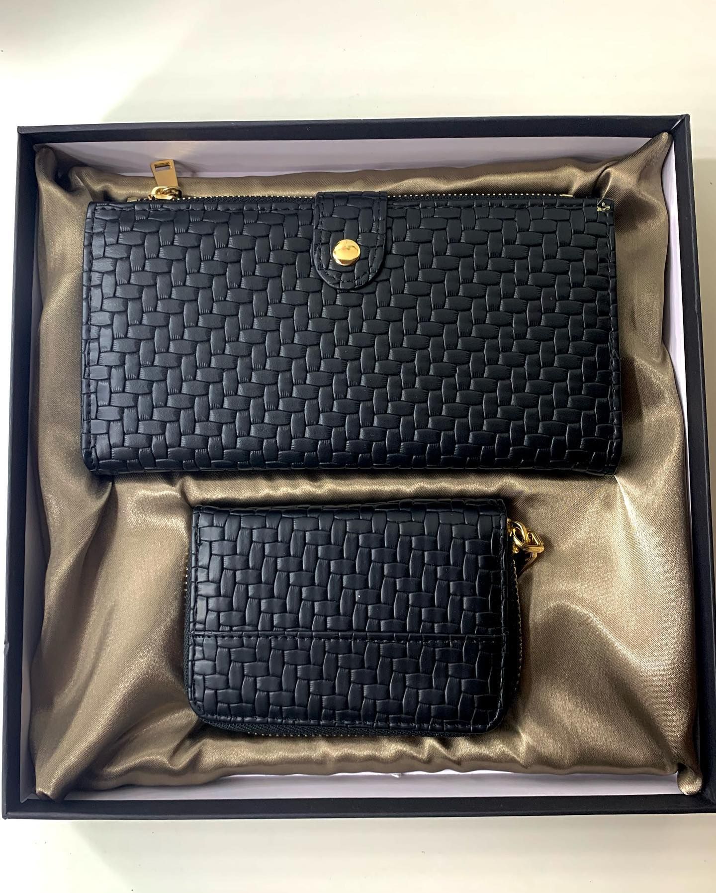 Una billetera negra y una billetera más pequeña están en una caja.