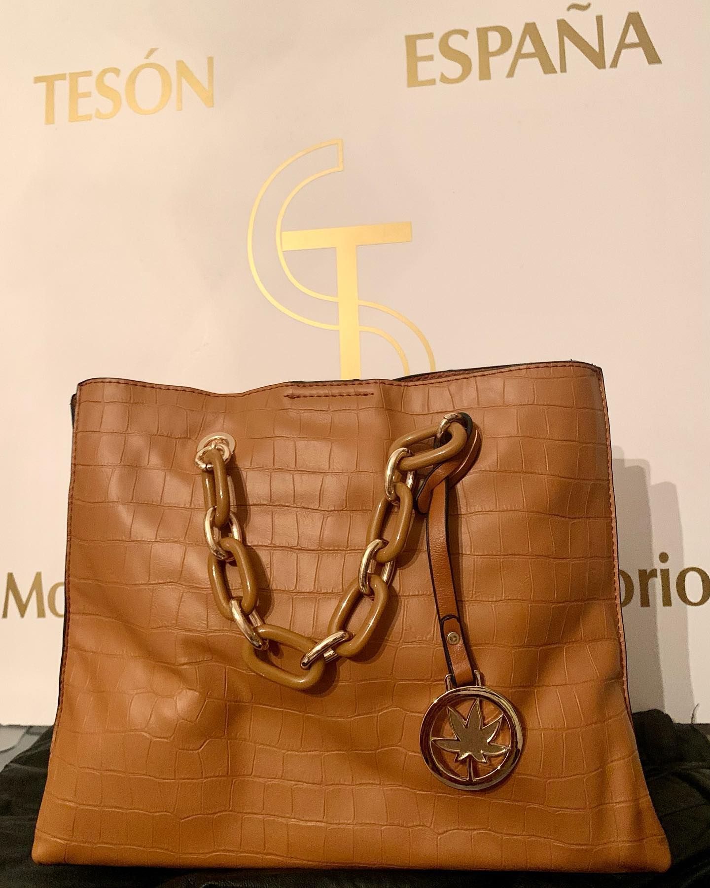 Un bolso de tesón marrón con una cadena dorada.