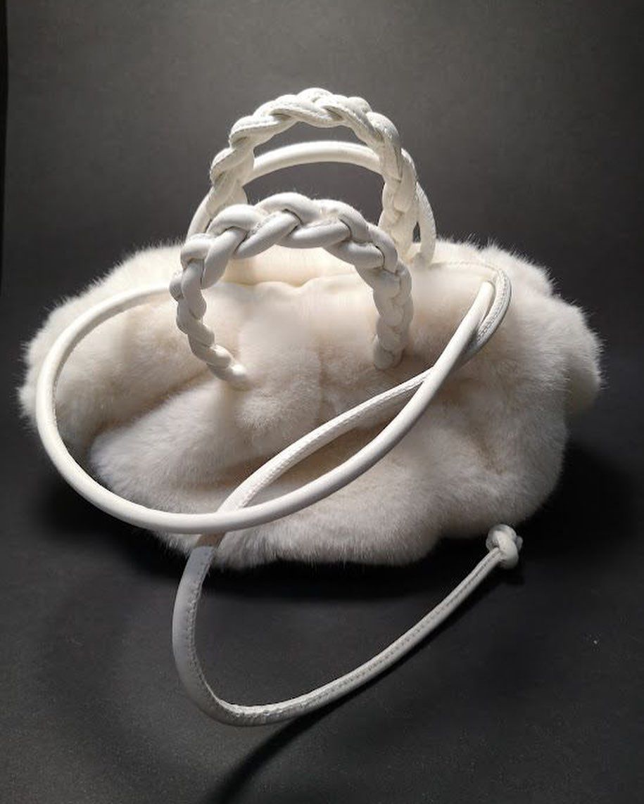 Un bolso peludo blanco con un asa trenzada