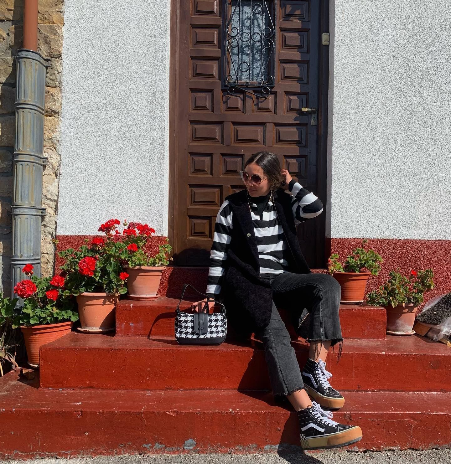 Una mujer está sentada en las escaleras de un edificio hablando por un teléfono celular.