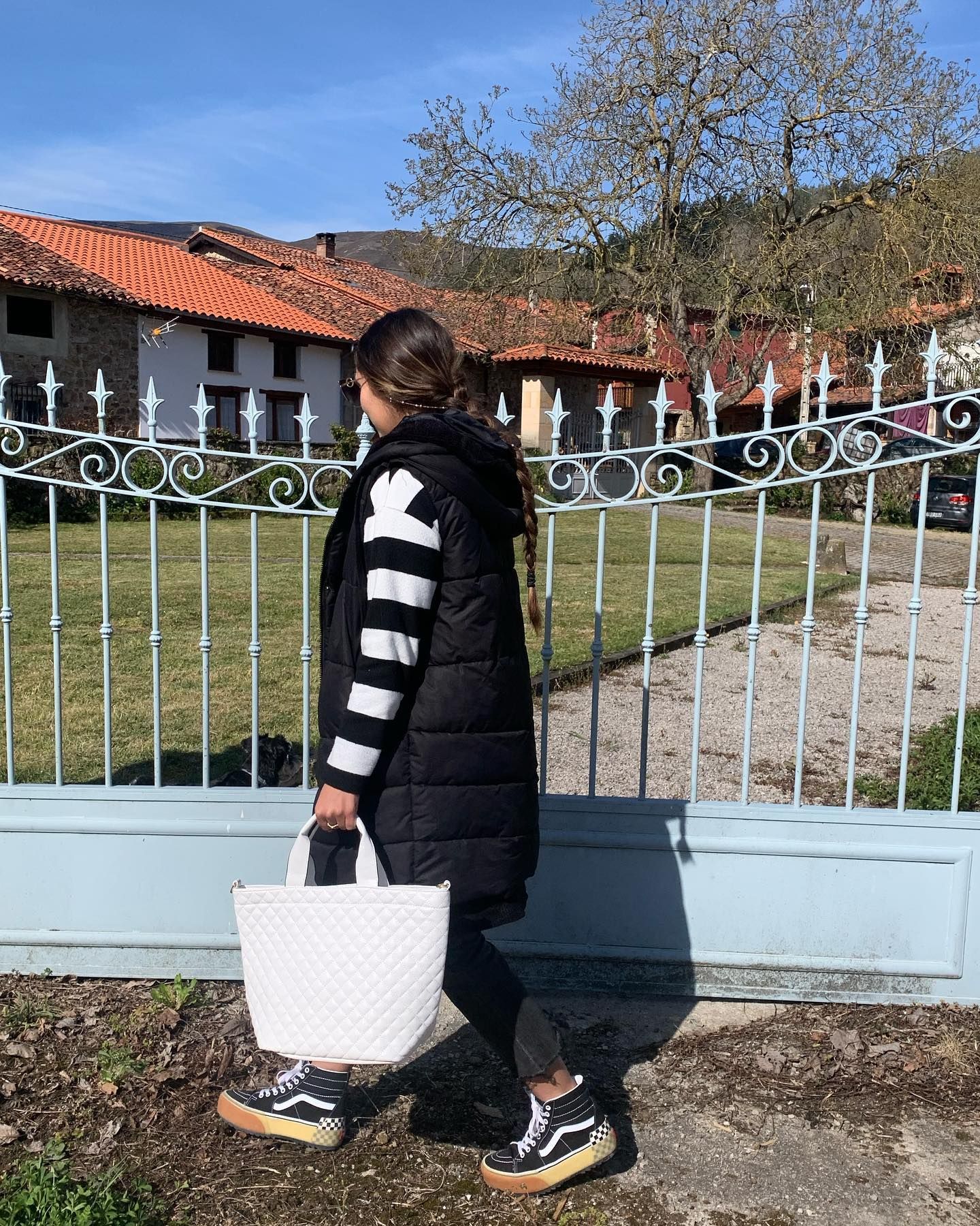 Una mujer con un chaleco negro lleva una bolsa blanca.