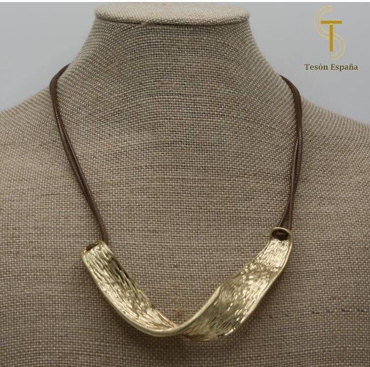 Un collar de oro está en un maniquí con la letra t en él.