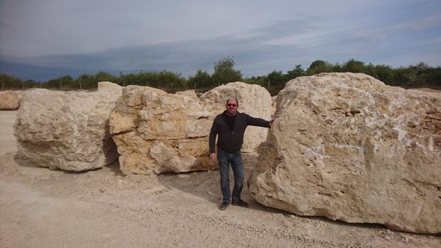 Homme habillé en noir appuyé sur une pierre