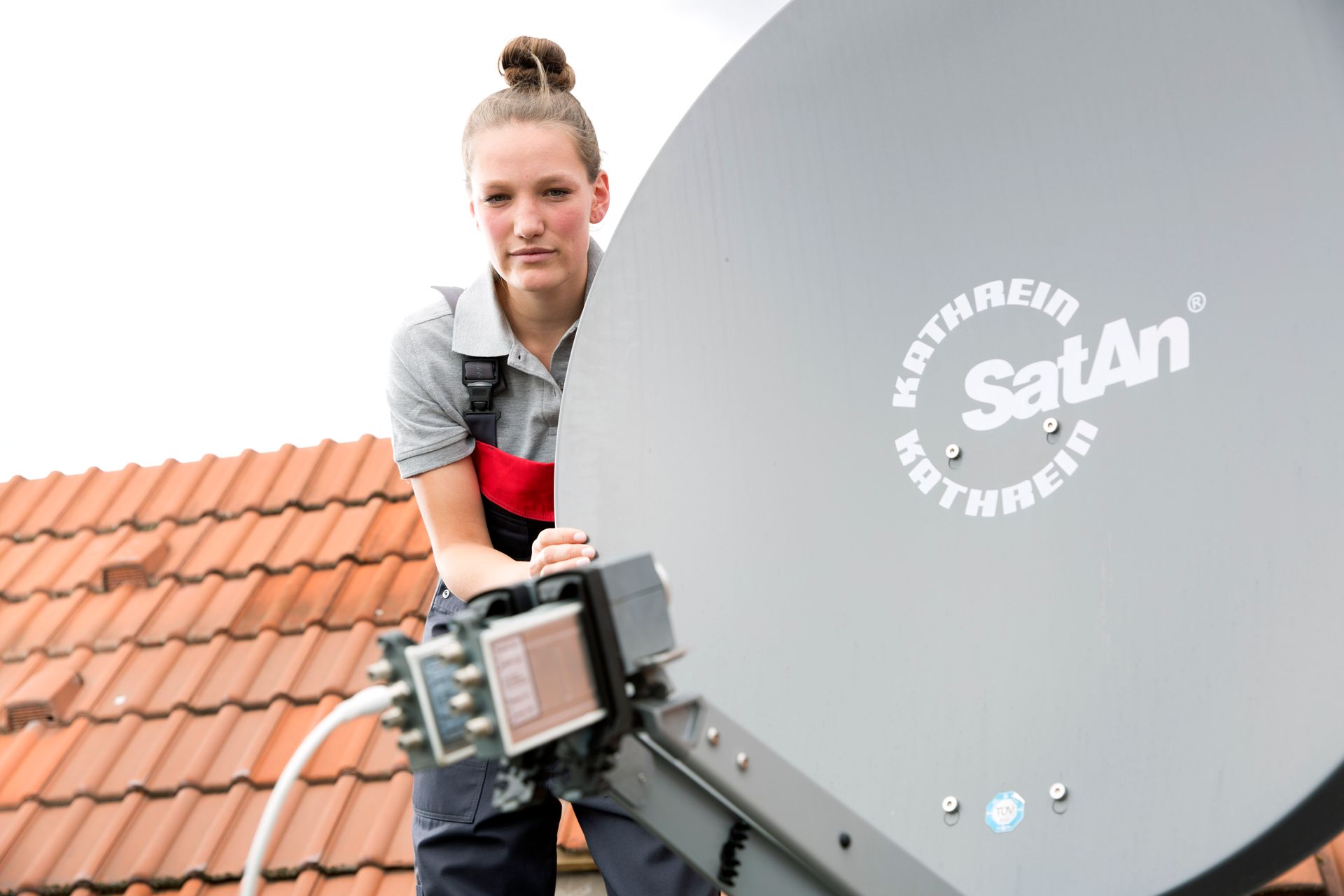 Auszubildende installiert Satellitenantennen auf einem Dach
