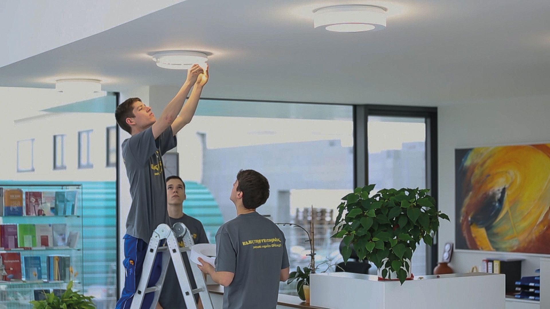 Auszubildende installieren Deckenleuchten in einem Büro