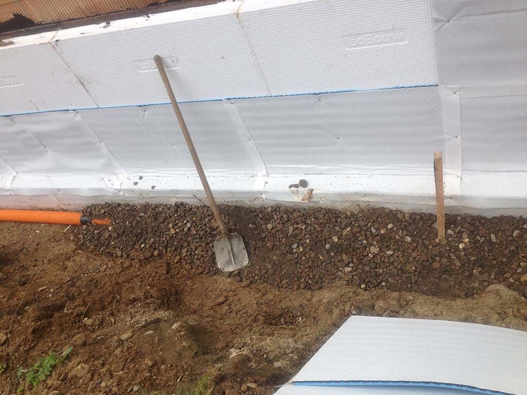 Eine Schaufel in einem Graben neben einer weißen Wand in Hüllhorst