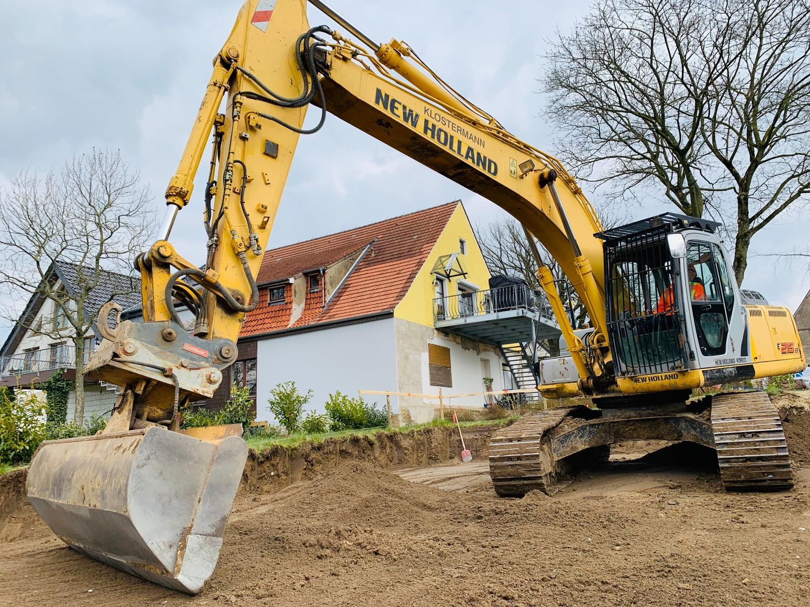 Ein gelb-schwarzer Bagger vor einem Haus in Bünde