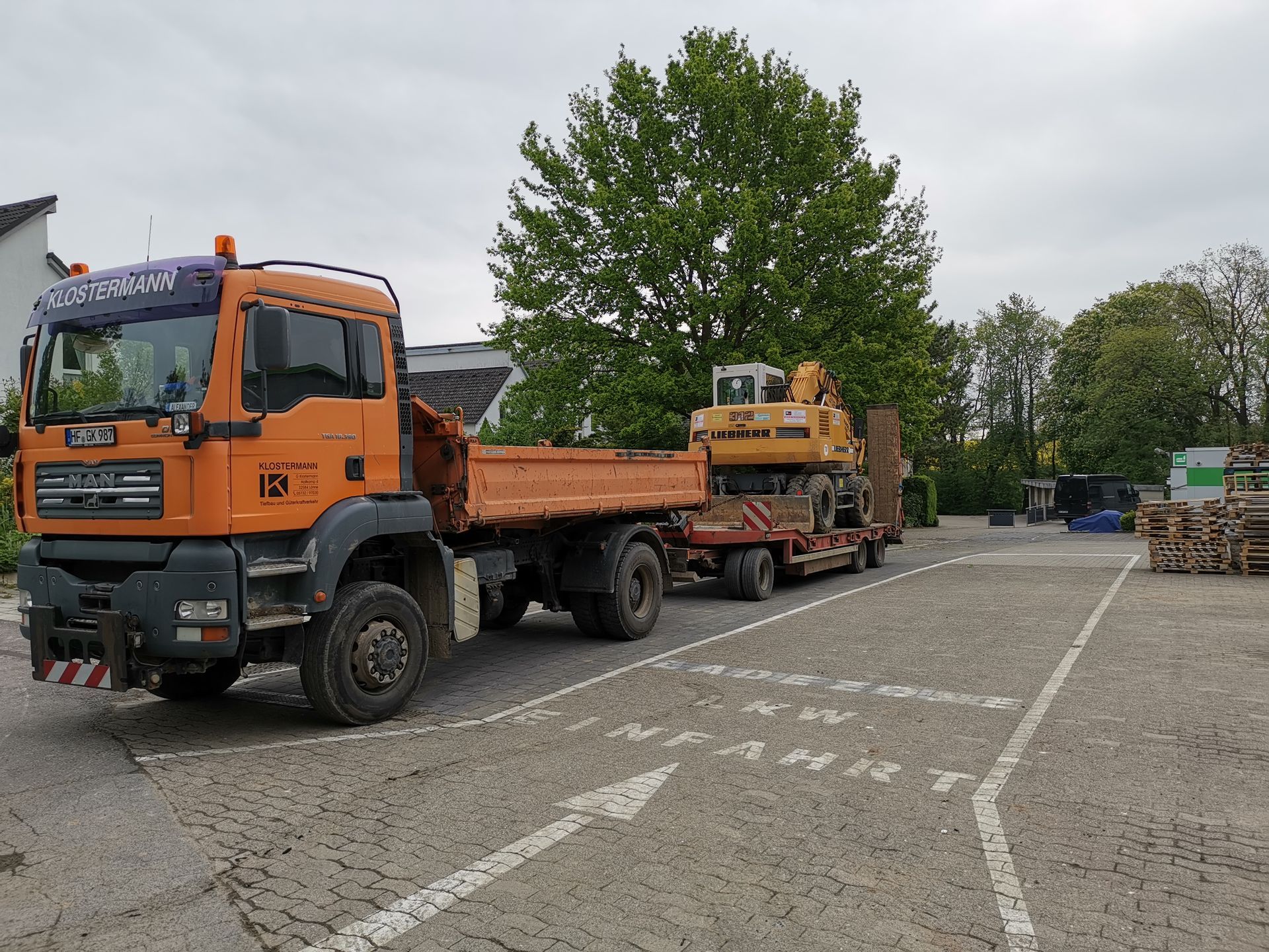 Ein orangefarbener Lkw mit einem Bagger auf dem Anhänger