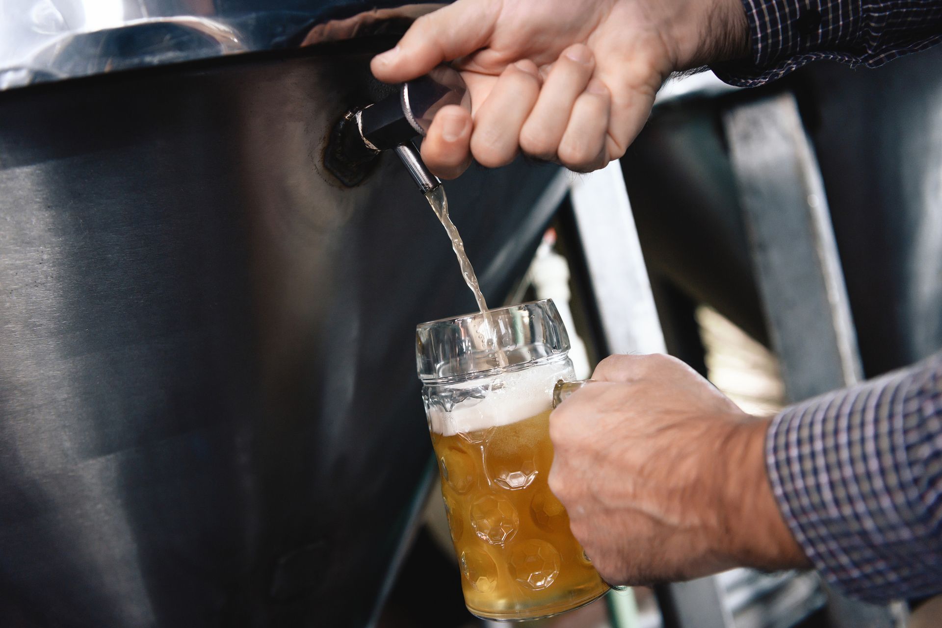 Un hombre está sirviendo cerveza en un vaso desde un grifo.