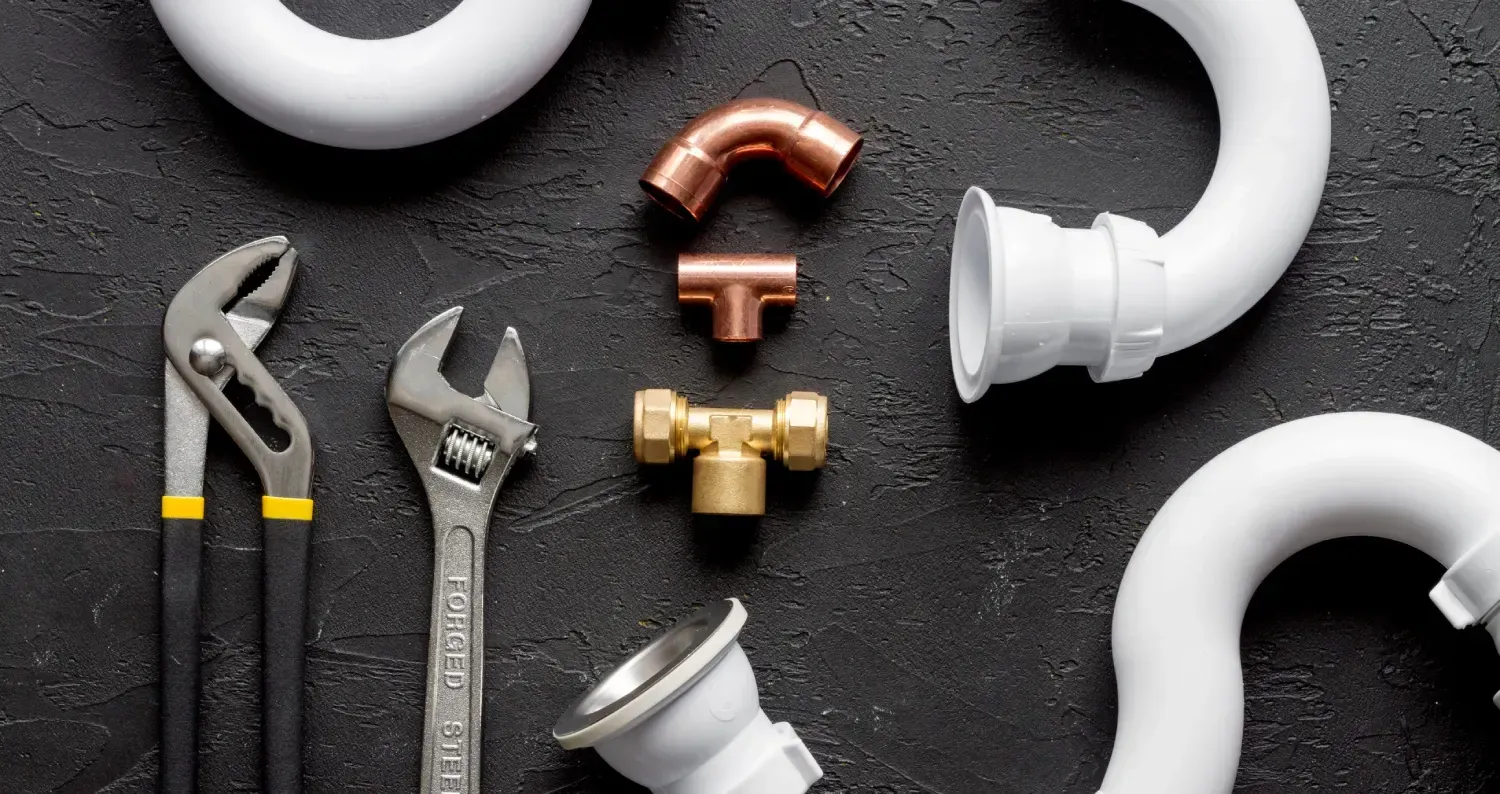 Una composición plana de herramientas de fontanería y componentes de tuberías de PVC blancas, incluyendo una llave inglesa