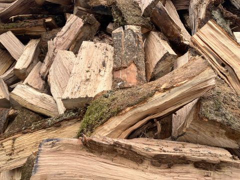 Bûches de bois de chauffage haché empilées, avec écorce et grain clair.