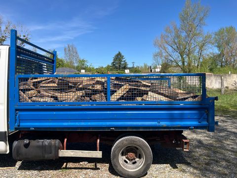 Camion plateau bleu chargé de ferraille, garé à l'extérieur sous un ciel dégagé