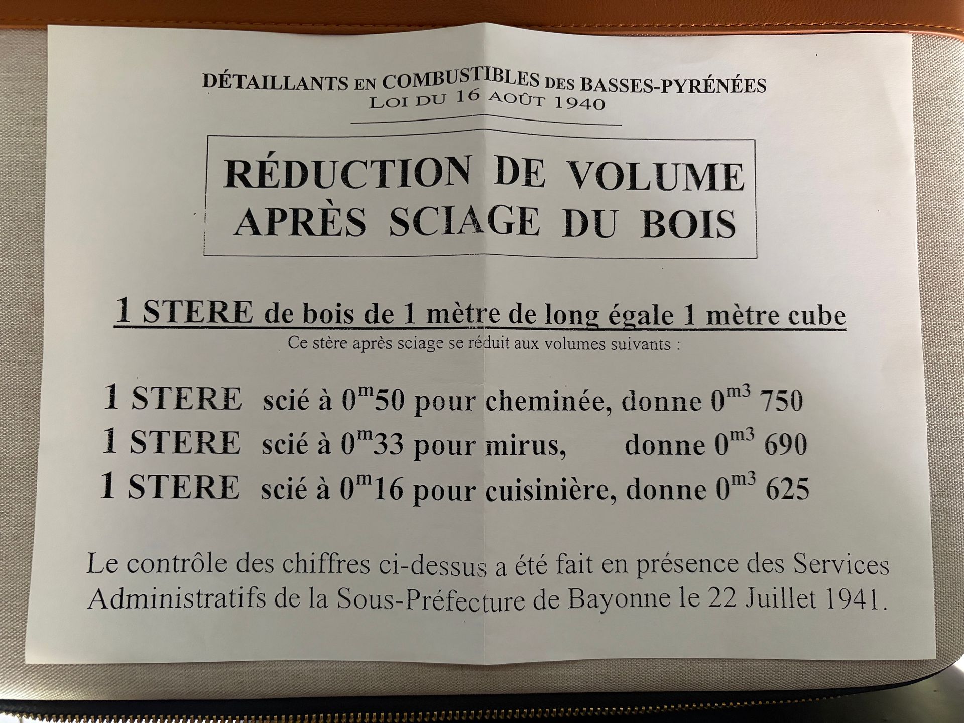 Panneau français annonçant des prix réduits sur le bois de chauffage en gros, papier blanc avec texte noir et bords usés.