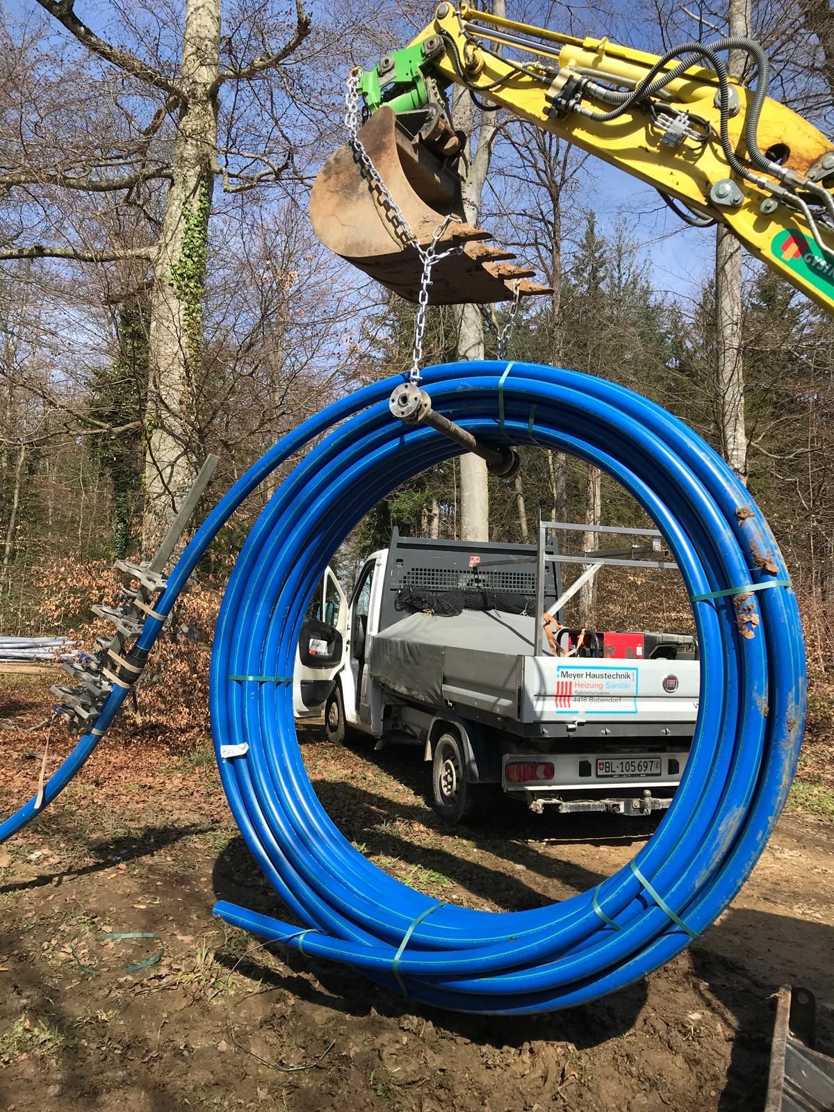 Behandschuhte Hände benutzen einen Schraubenschlüssel, um Kupferrohre unter einem Waschbecken zu reparieren.