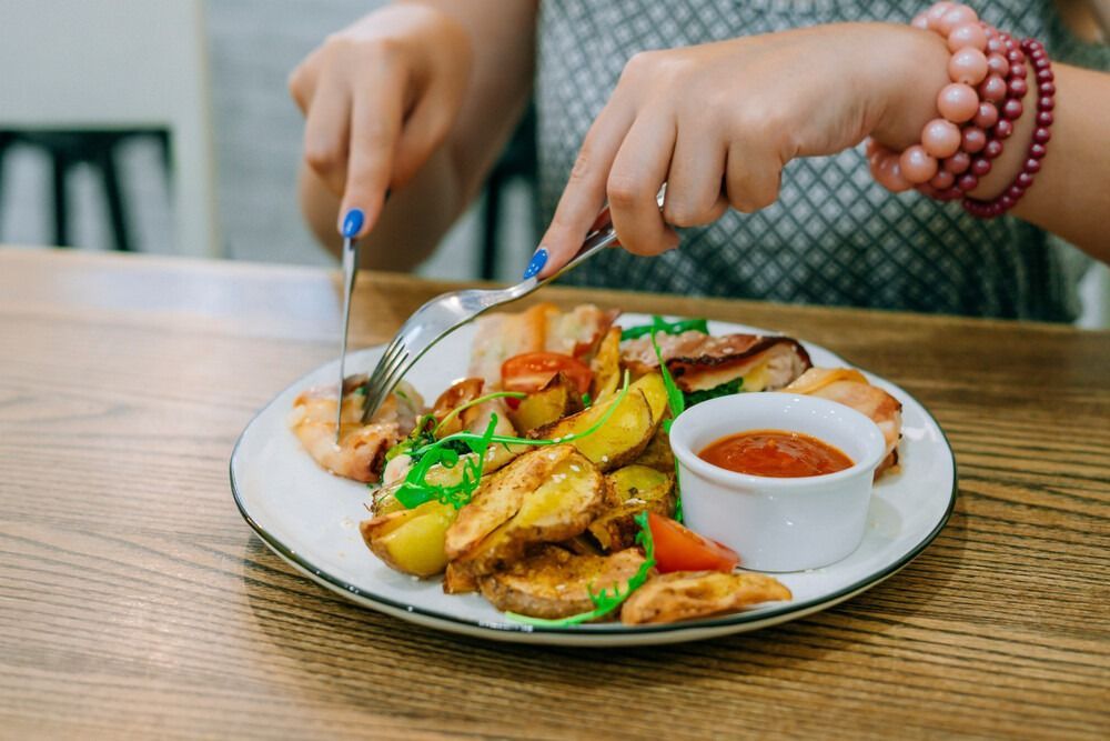 Una mujer está sentada en una mesa comiendo un plato de comida.