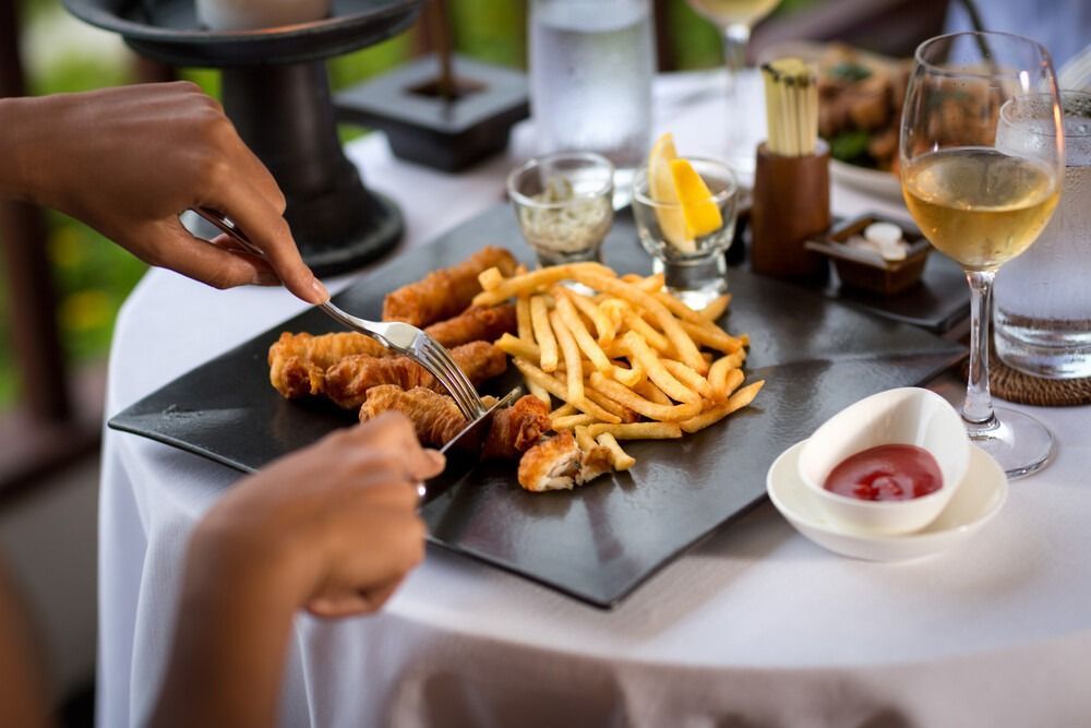 Una persona está comiendo pescado y patatas fritas en un restaurante.