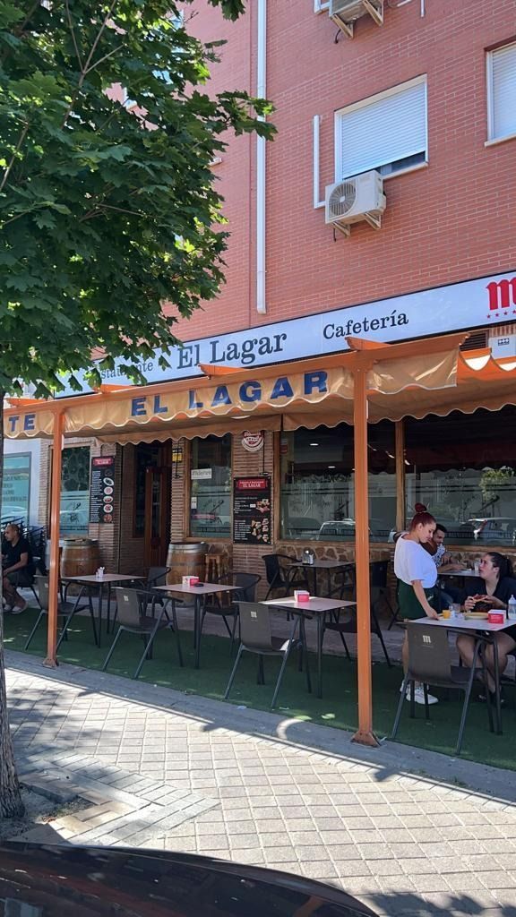 Un grupo de personas están sentadas en mesas afuera de un restaurante.