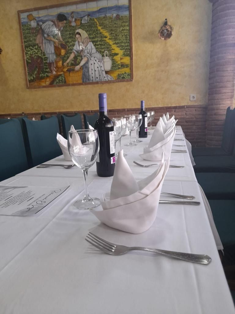 Una mesa larga con botellas de vino y copas encima.