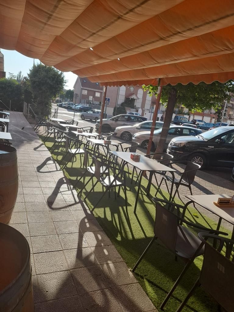 Un patio con mesas y sillas bajo un toldo naranja.