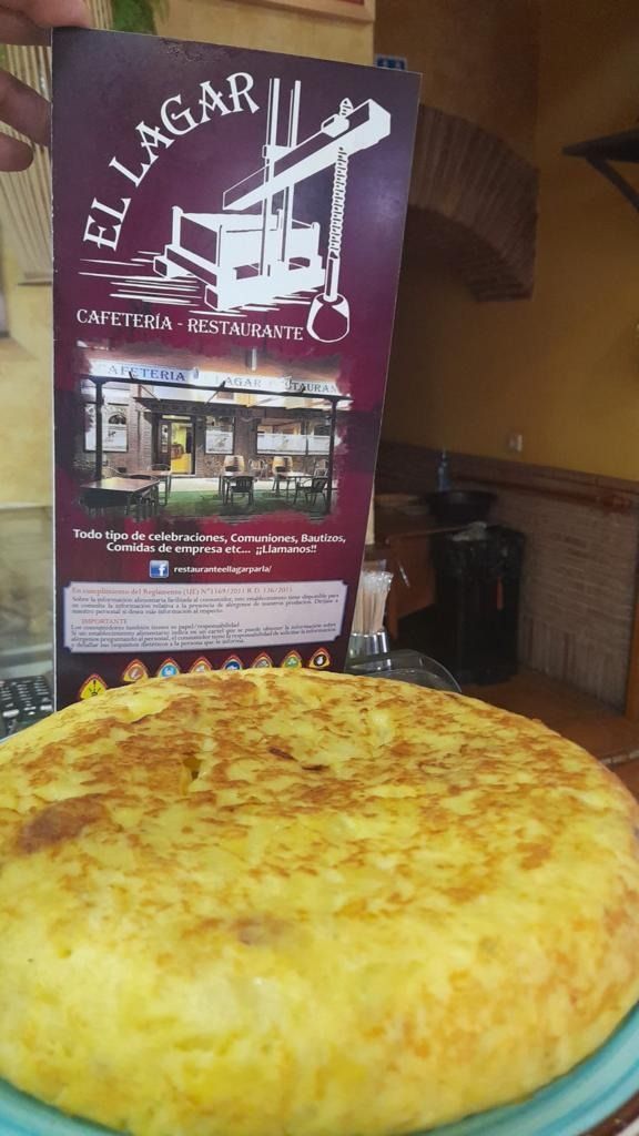 Una persona sostiene un menú al lado de una tortilla en un plato.