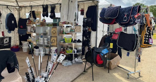 Étal de marché présentant des sacs à dos, des sacs et divers articles sous un auvent.