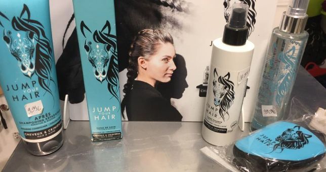 Présentoir de produits capillaires avec des flacons turquoise et blancs, une affiche et un peigne.